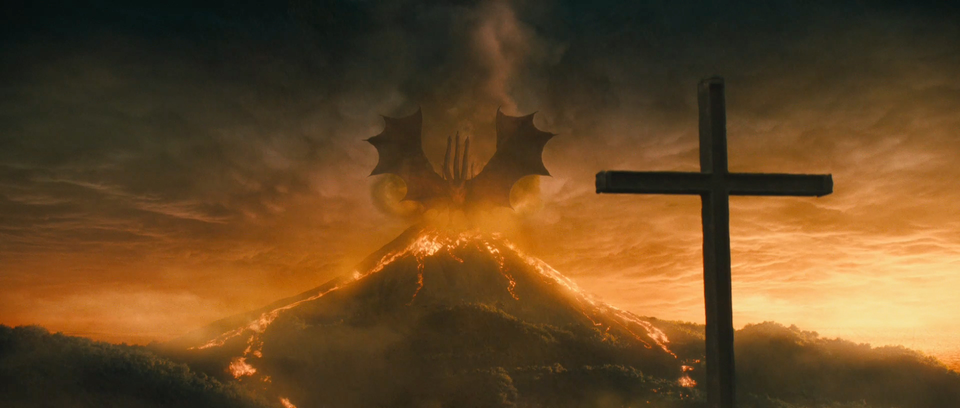 King Ghidorah sải rộng đôi cánh khổng lồ gầm vang trên đỉnh núi lửa Isla de Mara trước cây thánh giá trong bão sấm